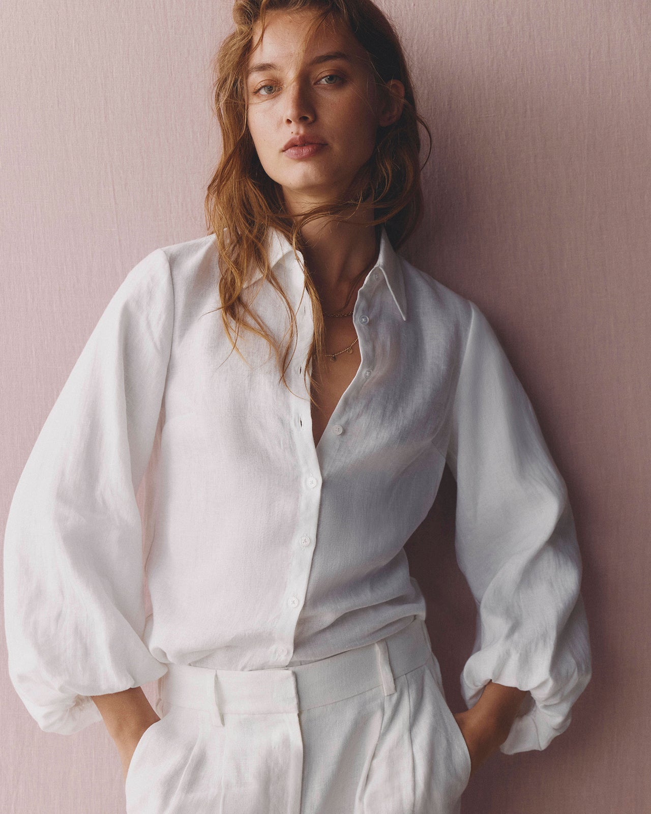 Woman wearing a white blouse against a pink wall
