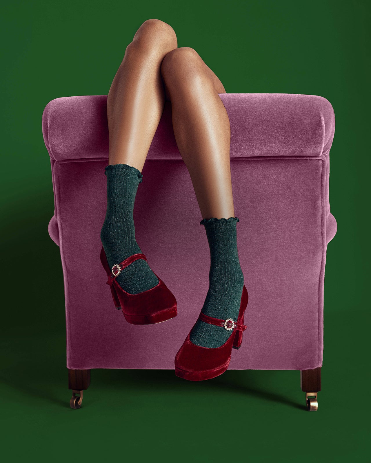 Purple armchair with legs wearing green socks and red shoes against a green background