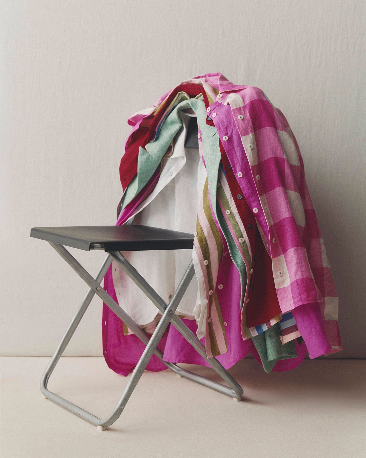 Colorful checkered towel draped over a black folding chair against a white wall.