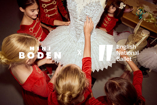 Children in red outfits interacting with a white ballet costume, featuring Mini Boden and English National Ballet logos.