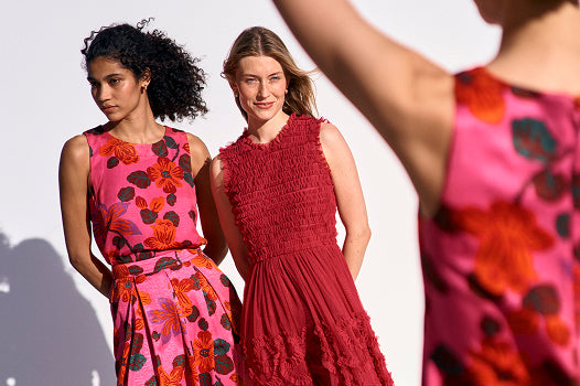 Two women wearing colorful dresses with floral patterns against a white background