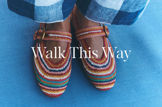 Colorful striped shoes worn with blue checkered pants on a blue surface, with text 'Walk This Way'.