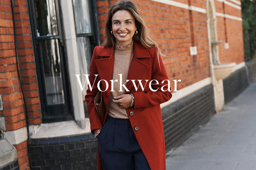 Woman wearing a red coat standing in front of a brick building with 'Workwear' text overlay.