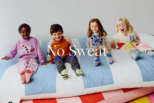 Four children sitting on a colorful bed with 'No Sweat' text overlay.