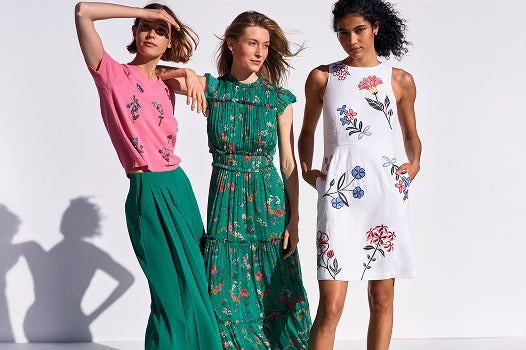 Three women wearing floral dresses on a white background