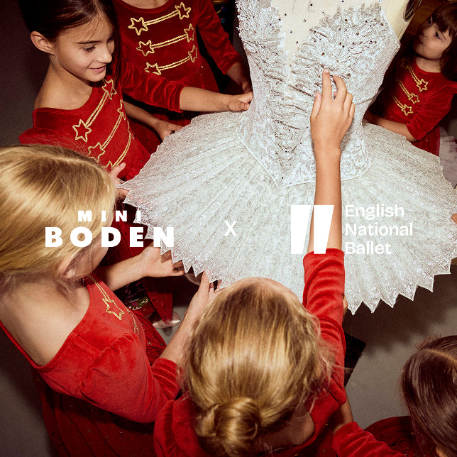 Children in red outfits interacting with a white ballet costume, featuring Mini Boden and English National Ballet logos.
