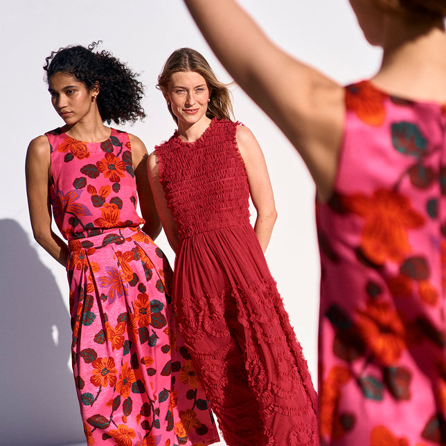 Two women wearing colorful dresses with floral patterns against a white background