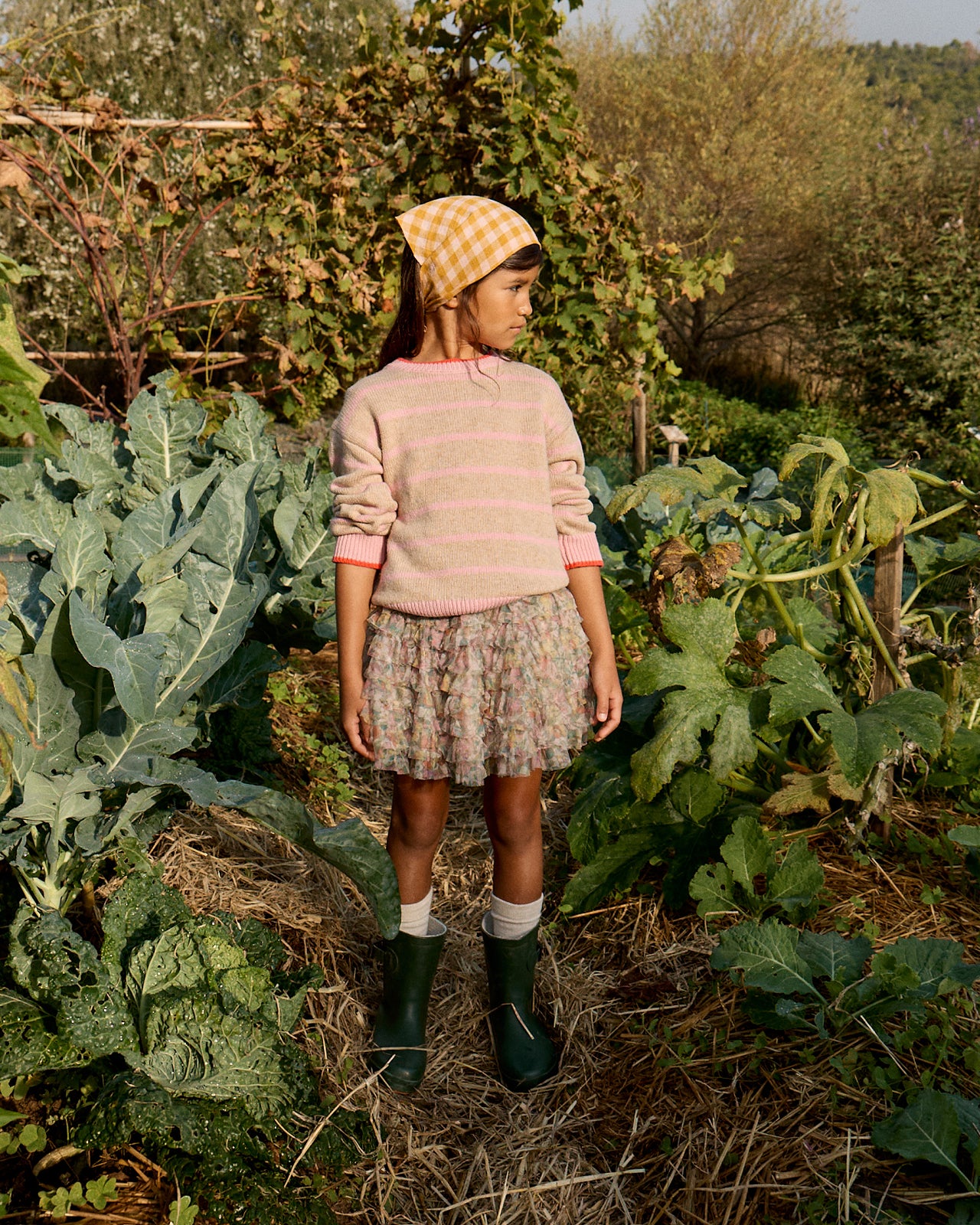 Young girl standing in a garden surrounded by leafy plants
