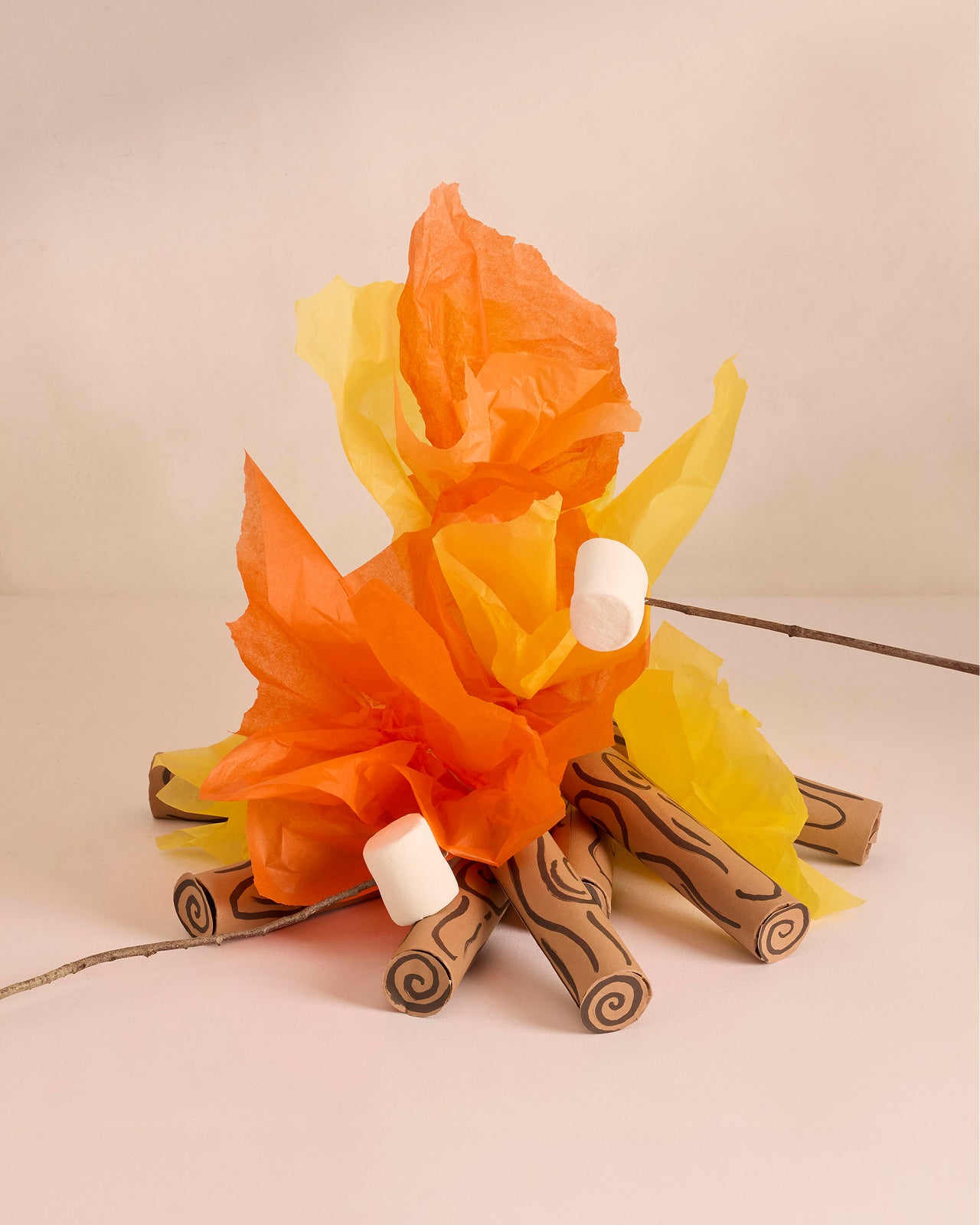 Decorative campfire made of paper and wooden sticks on a beige background