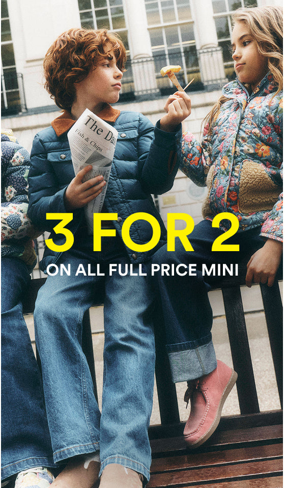 Three children sitting on a wooden bench outdoors, wearing colorful puffer jackets and jeans. Large yellow text overlays the center reading '3 FOR 2 ON ALL FULL PRICE MINI'.