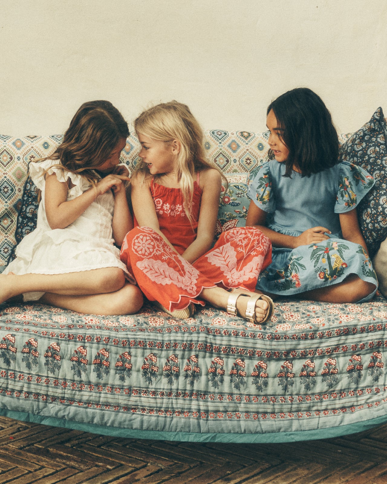 Three young girls sitting on a patterned couch
