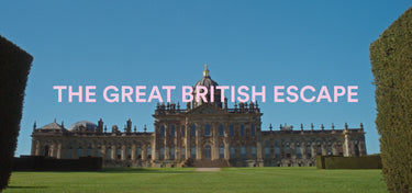 A scenic photograph of a grand historic mansion with manicured hedges and a green lawn under a clear blue sky, with the text 'THE GREAT BRITISH ESCAPE' overlaid in pink across the center.
