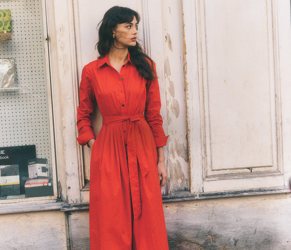 Woman wearing a red dress standing in front of a window with a store display.