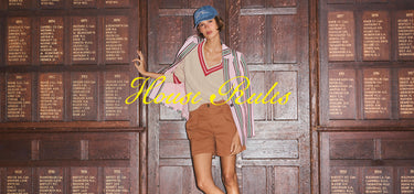 Woman posing in front of a wooden panel with engraved text, wearing a striped shirt and shorts.