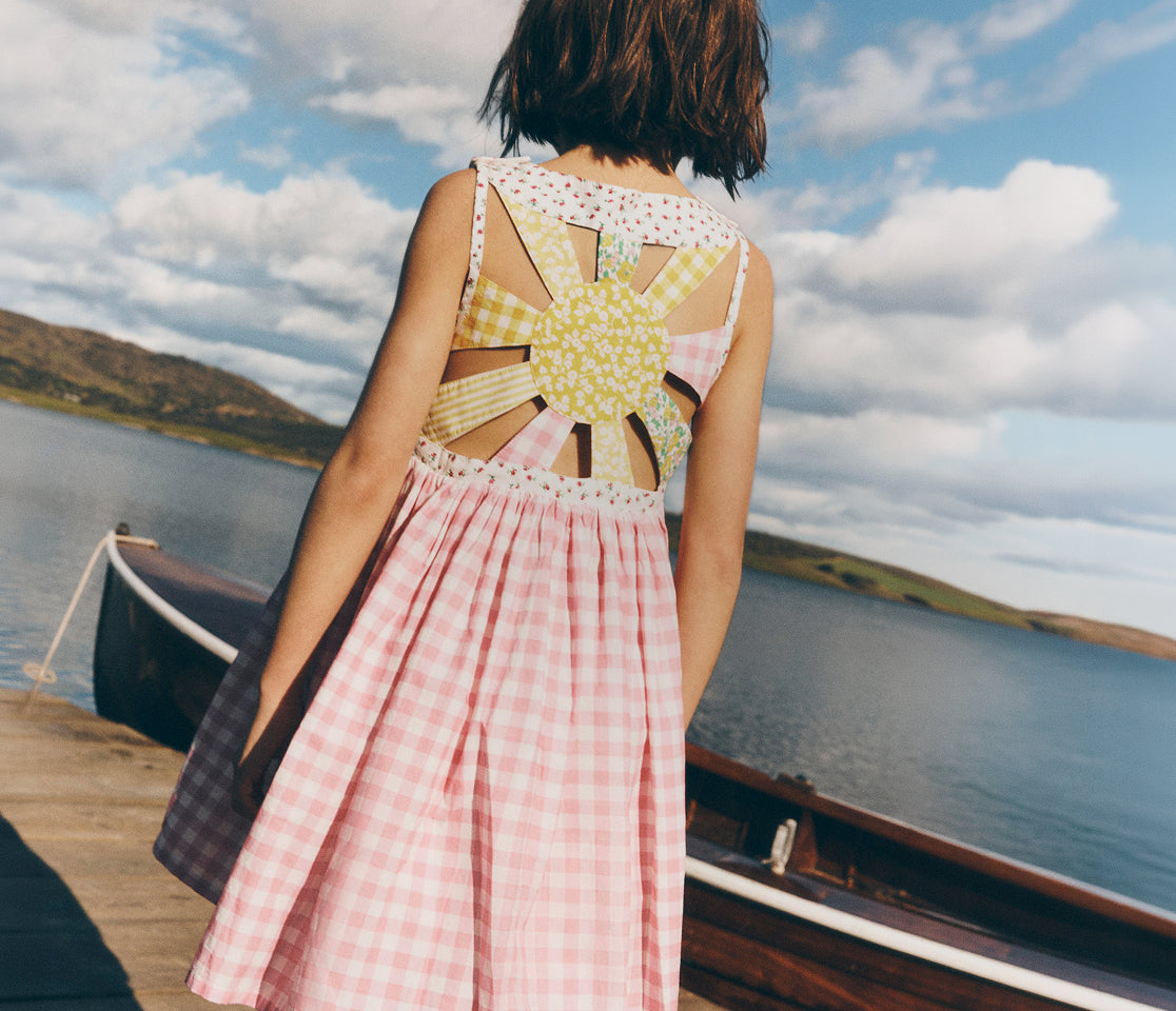 Woman in a colorful dress standing by a lake with mountains in the background