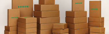 Stacks of brown boxes with 'Boden' branding on a white background