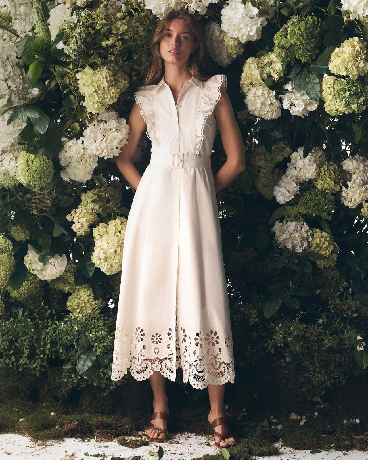 Woman in a white dress standing against a floral background