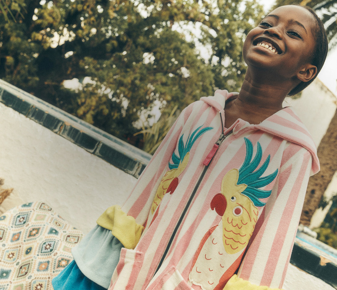 Woman wearing a colorful jacket with a cartoon design, standing outdoors.