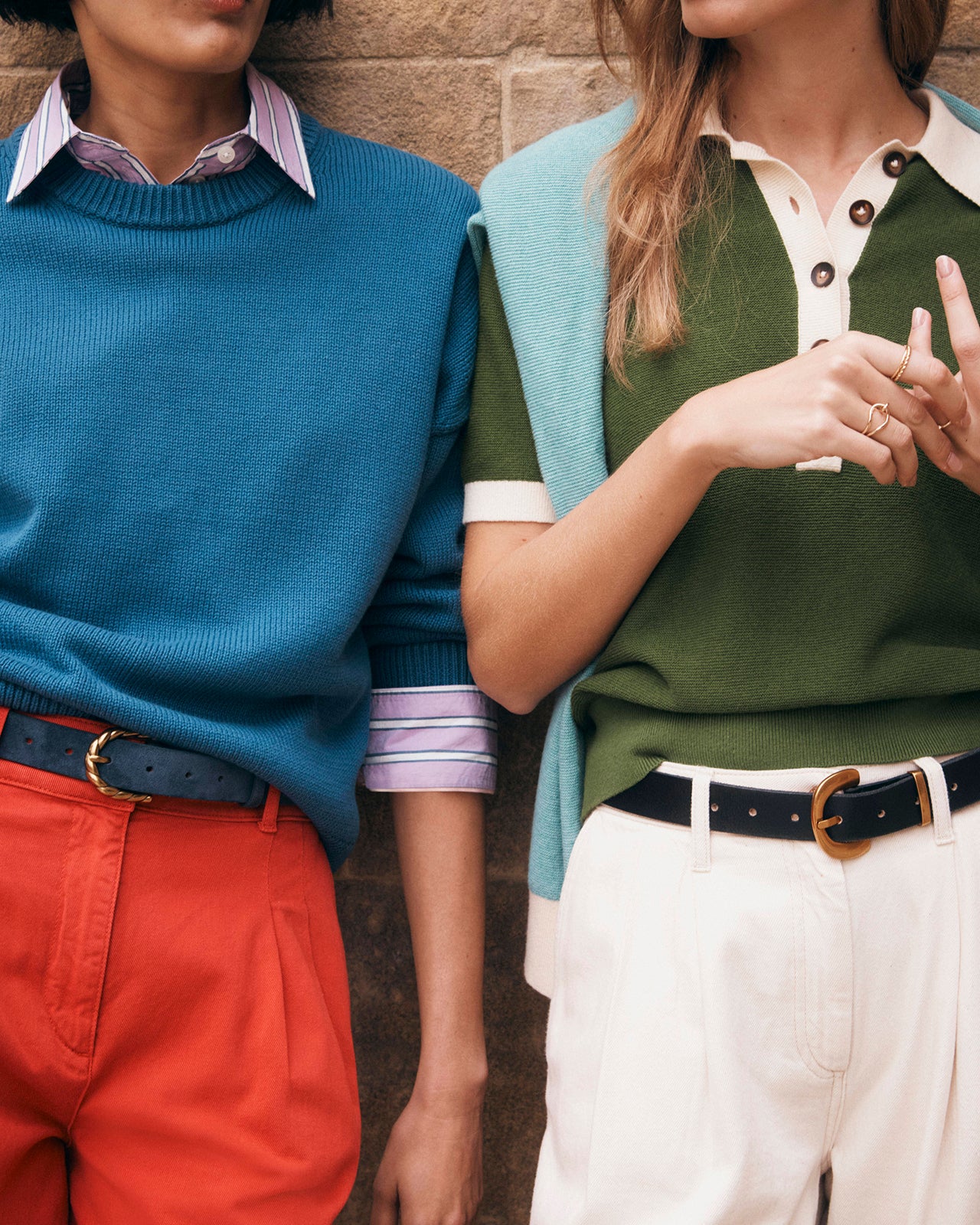 Two people wearing colorful clothing with a brick wall background