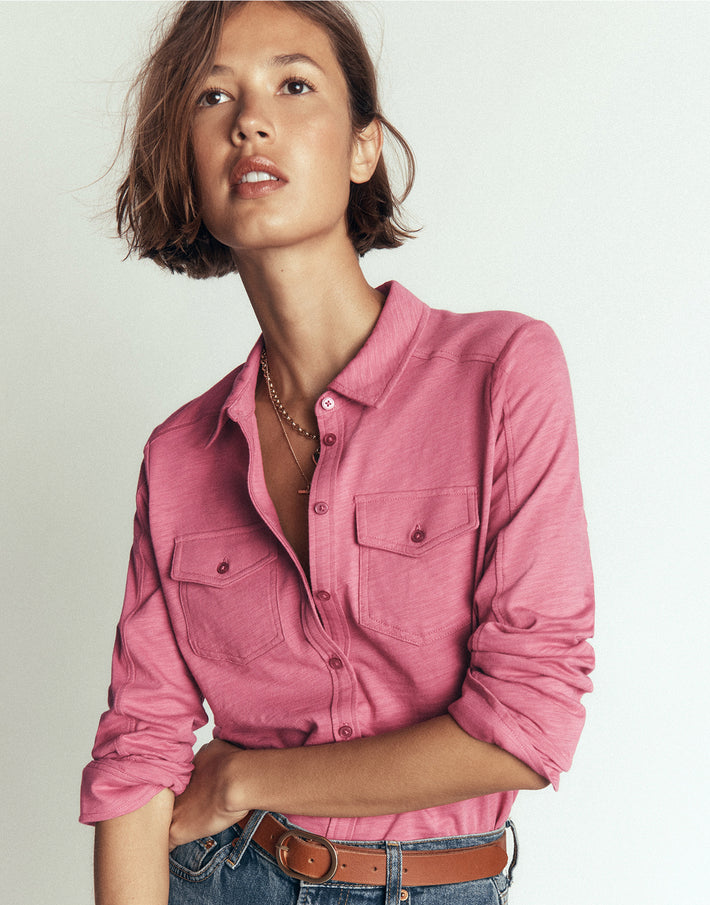 Person wearing a pink shirt and jeans on a plain background