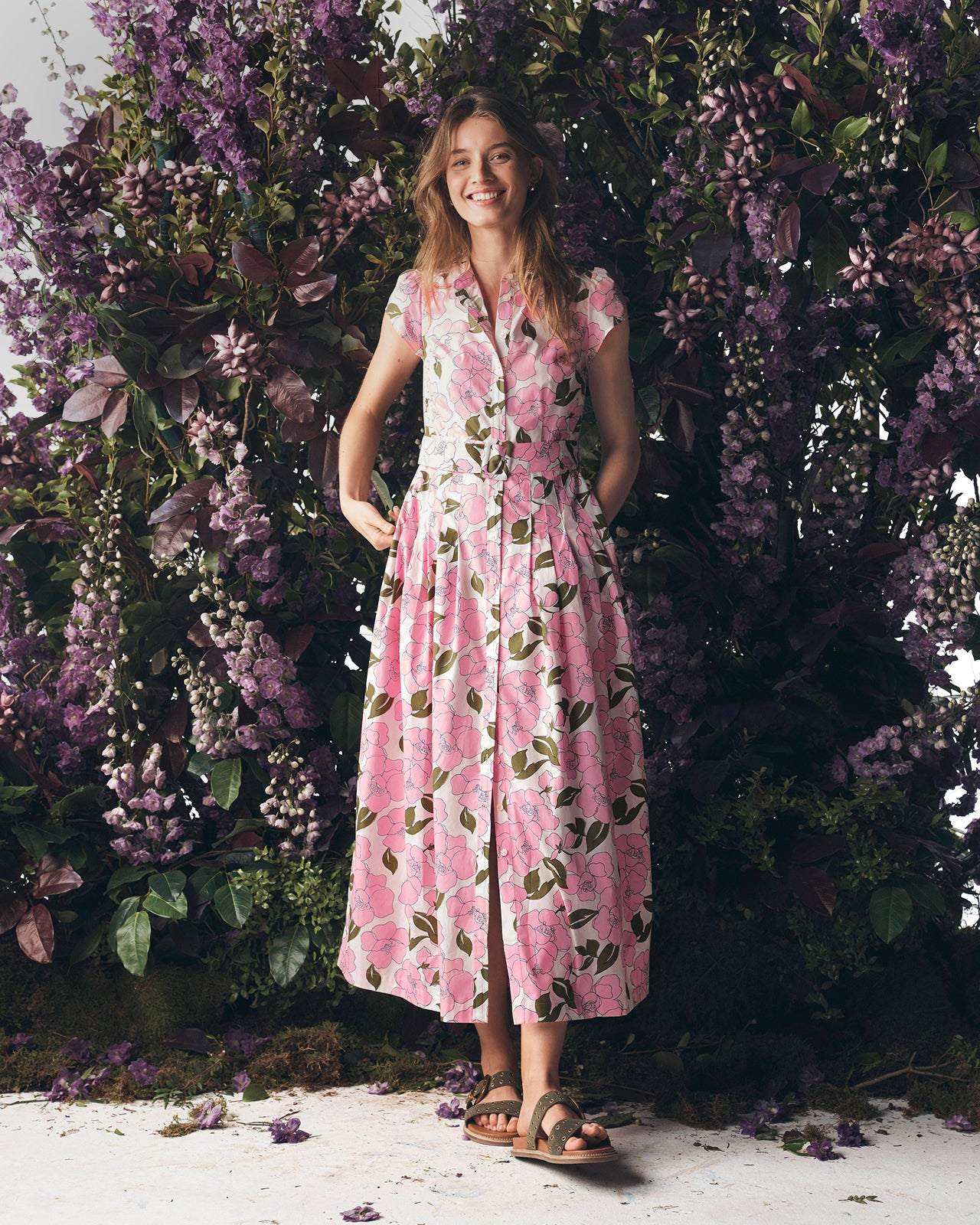 Woman in a pink floral dress standing in front of a floral backdrop