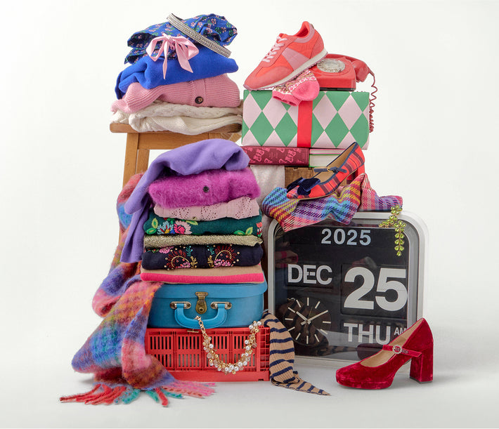 Stack of clothes, shoes, and accessories with a calendar indicating December 25th on a white background.