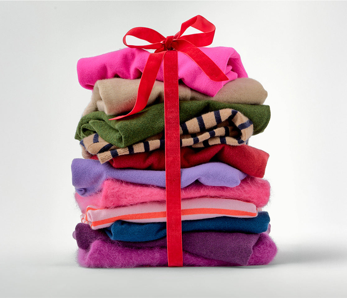 Stack of colorful folded clothes tied with a red ribbon on a light gray background