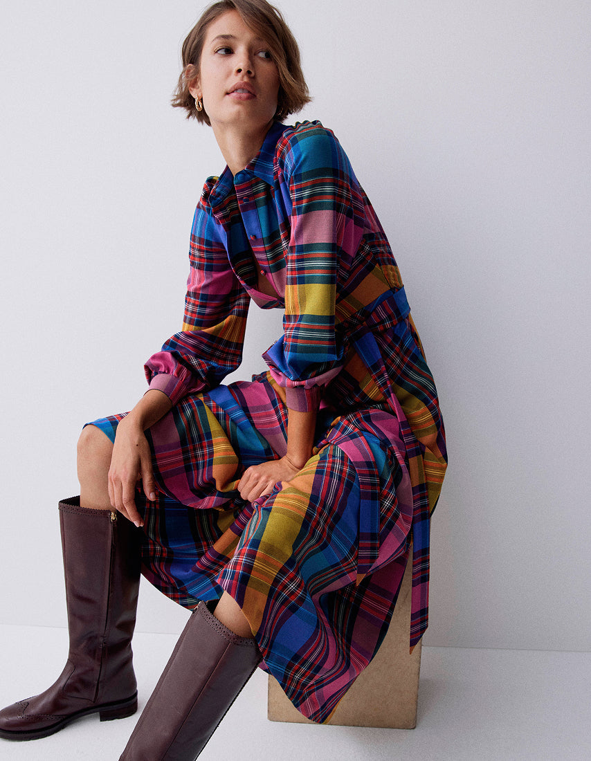 Woman wearing a colourful plaid dress and knee-high boots on a white background