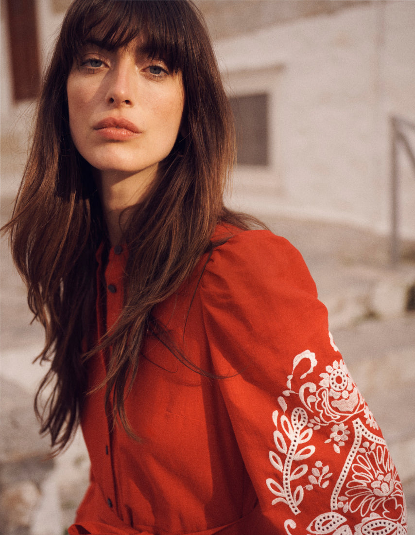 Woman wearing a red jacket with white embroidery in an outdoor setting