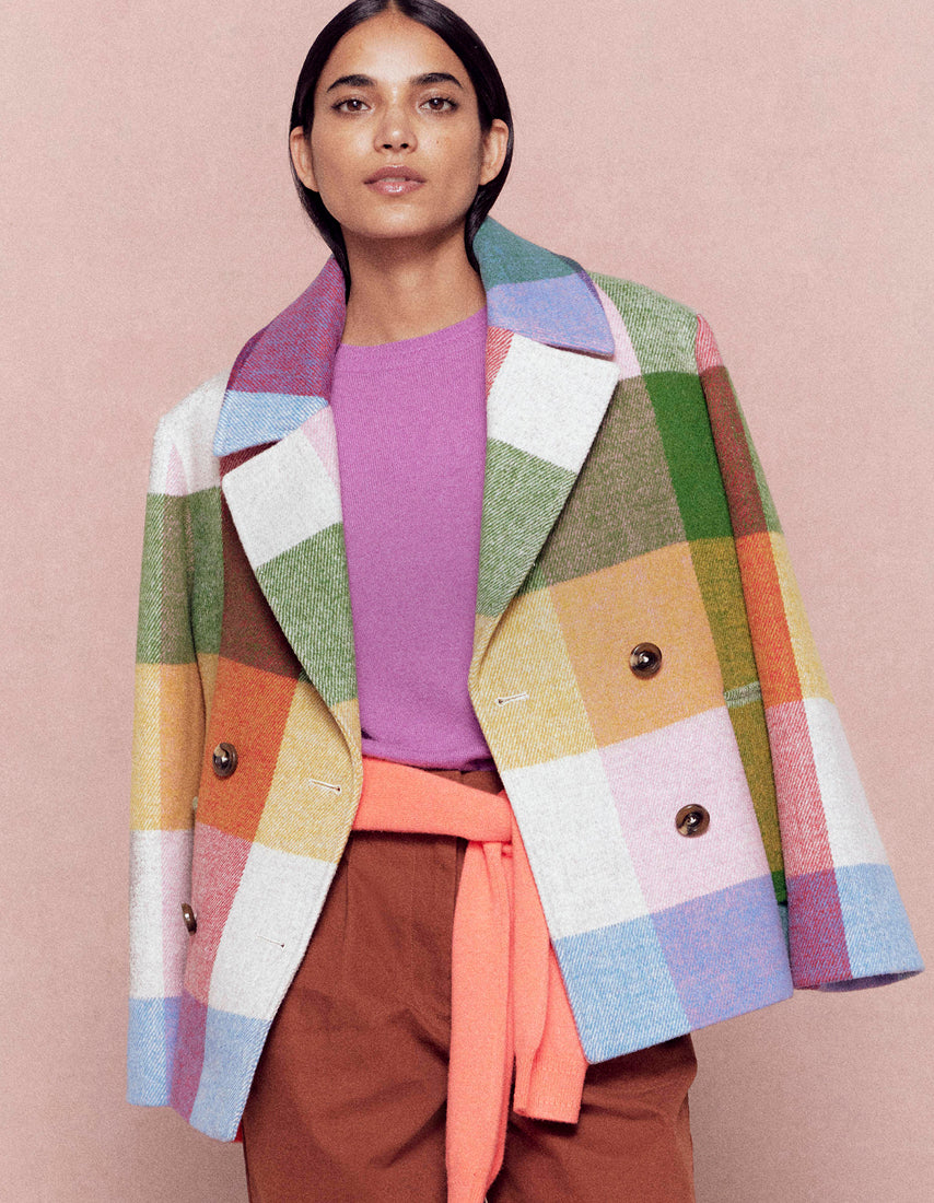 Woman wearing a colorful patchwork coat against a pink background