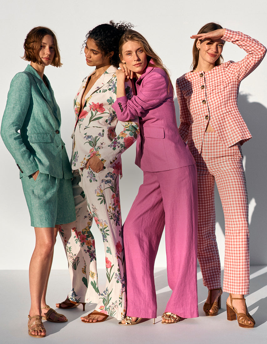 Four women in colorful outfits standing against a white background
