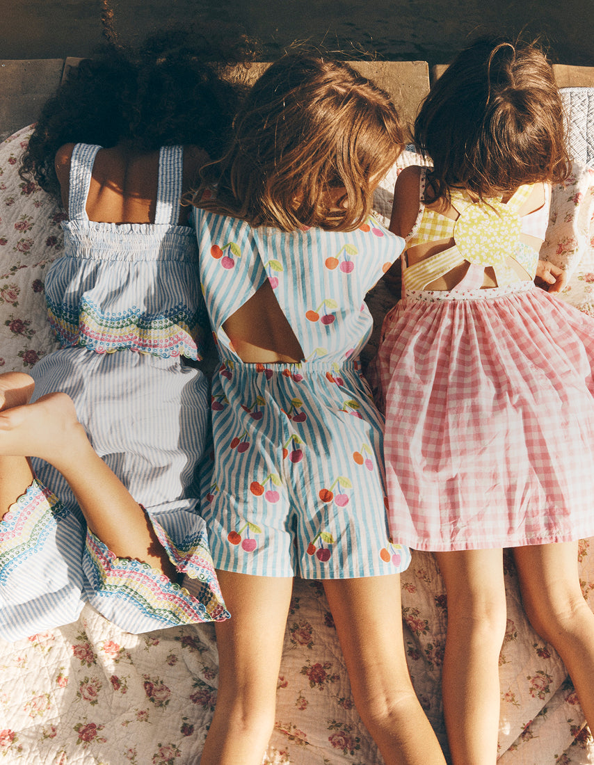 Three children wearing colorful outfits sitting on a floral-patterned couch.