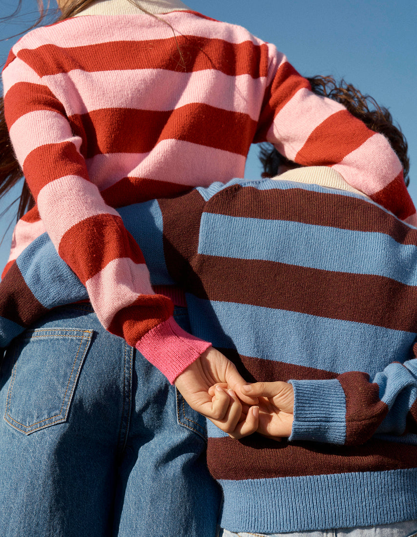 Two people wearing colorful striped sweaters against a clear blue sky.