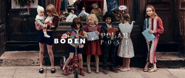 A group of children standing in front of a shop doorway wearing colorful striped and patterned outfits, with the text 'BODEN x POLAKI POST' overlaid across the center.
