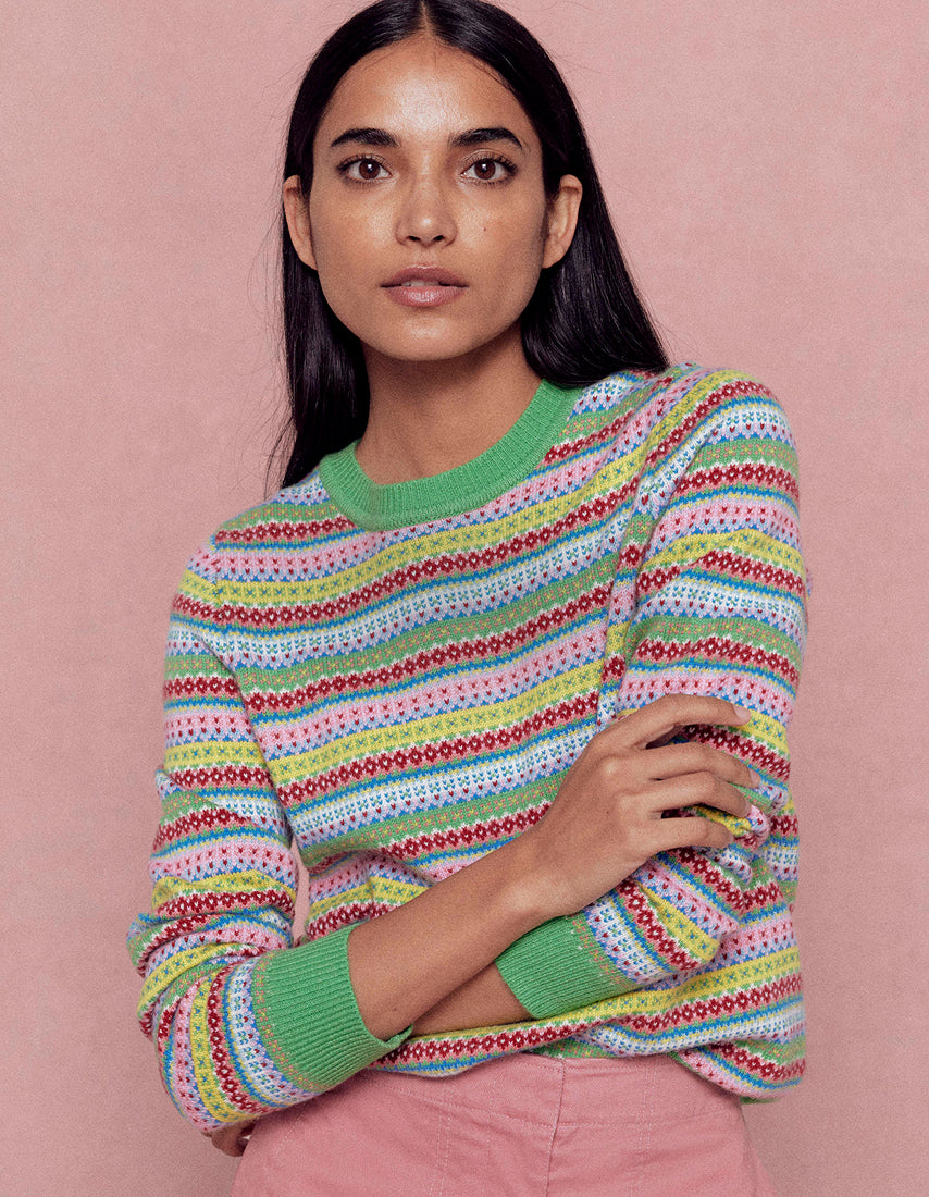 Woman wearing a colorful striped sweater against a pink background