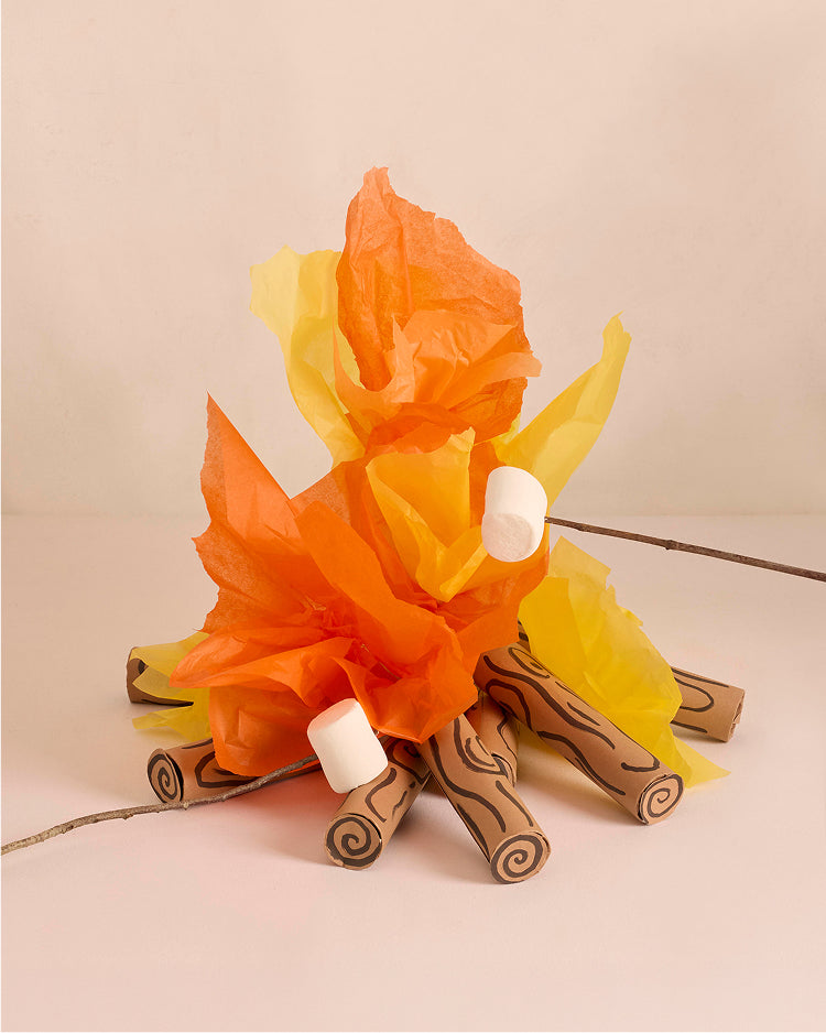 Artificial campfire made of paper with wooden logs on a beige background