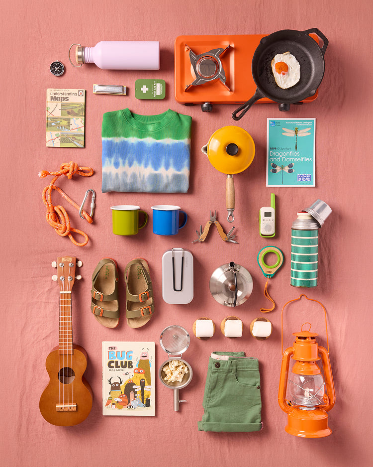 Collection of various items including a ukulele, shoes, and camping gear on a pink background