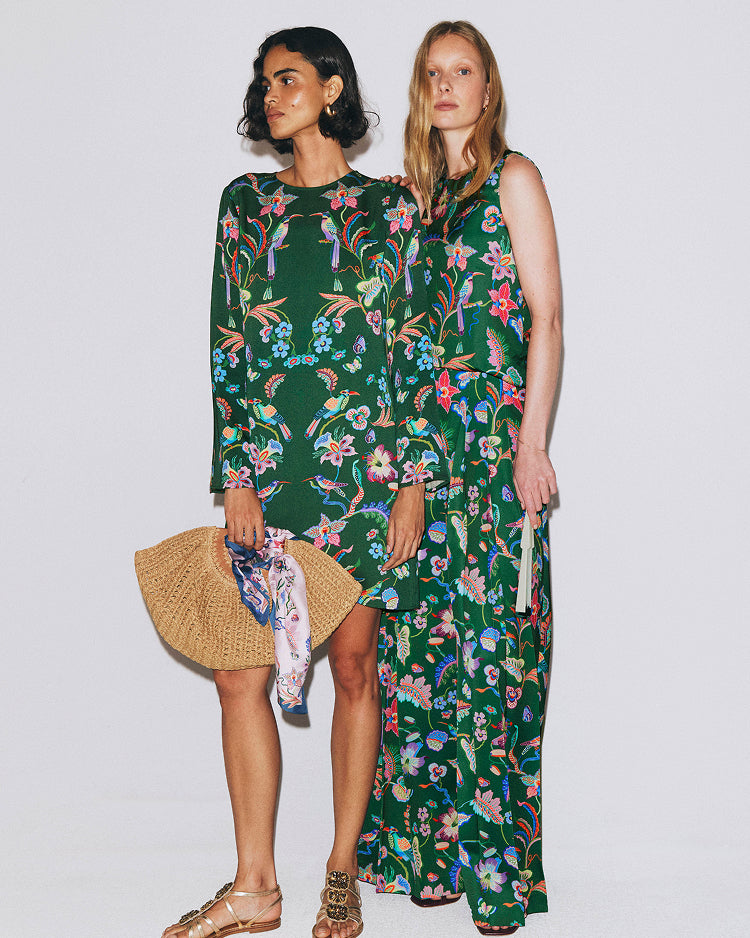Two women wearing green floral dresses on a white background