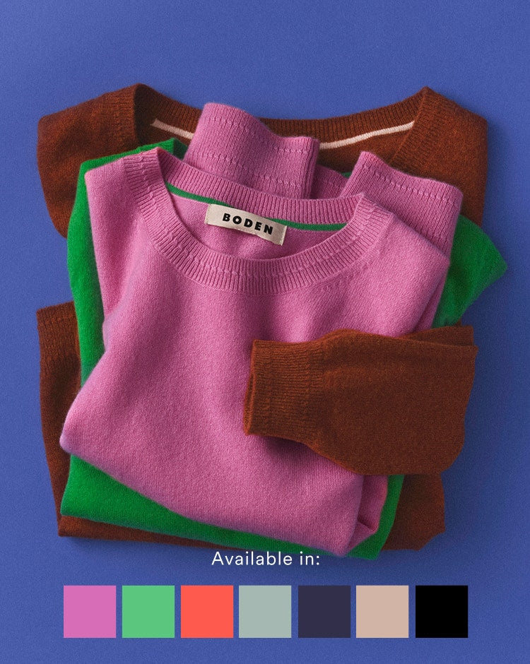 Stack of folded sweaters with a visible brand label on a blue background