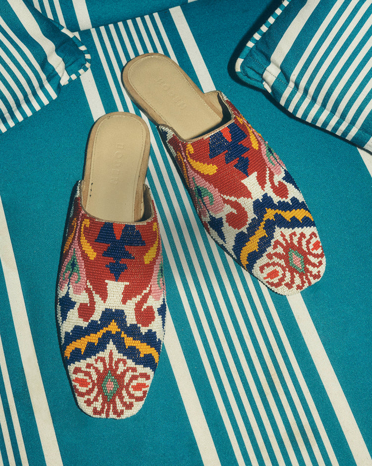 Colorful embroidered slippers on a blue and white striped surface