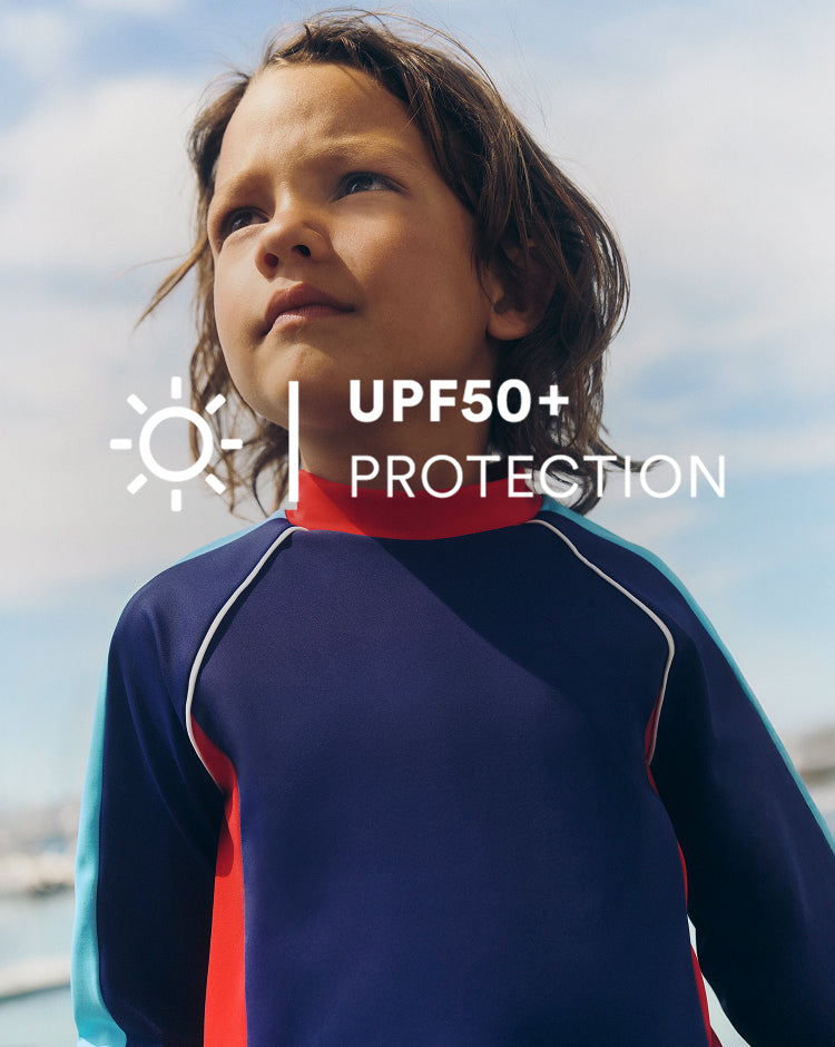 Child wearing a blue and red swimsuit with UPF50+ protection text