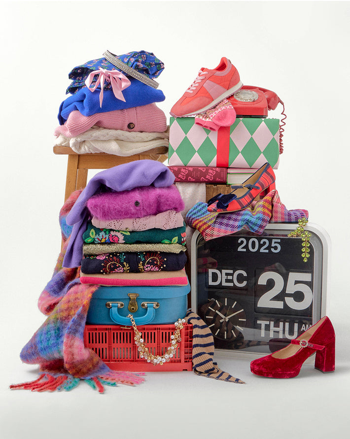 Stack of colorful clothing, shoes, and accessories with a calendar showing December 25th on a white background.