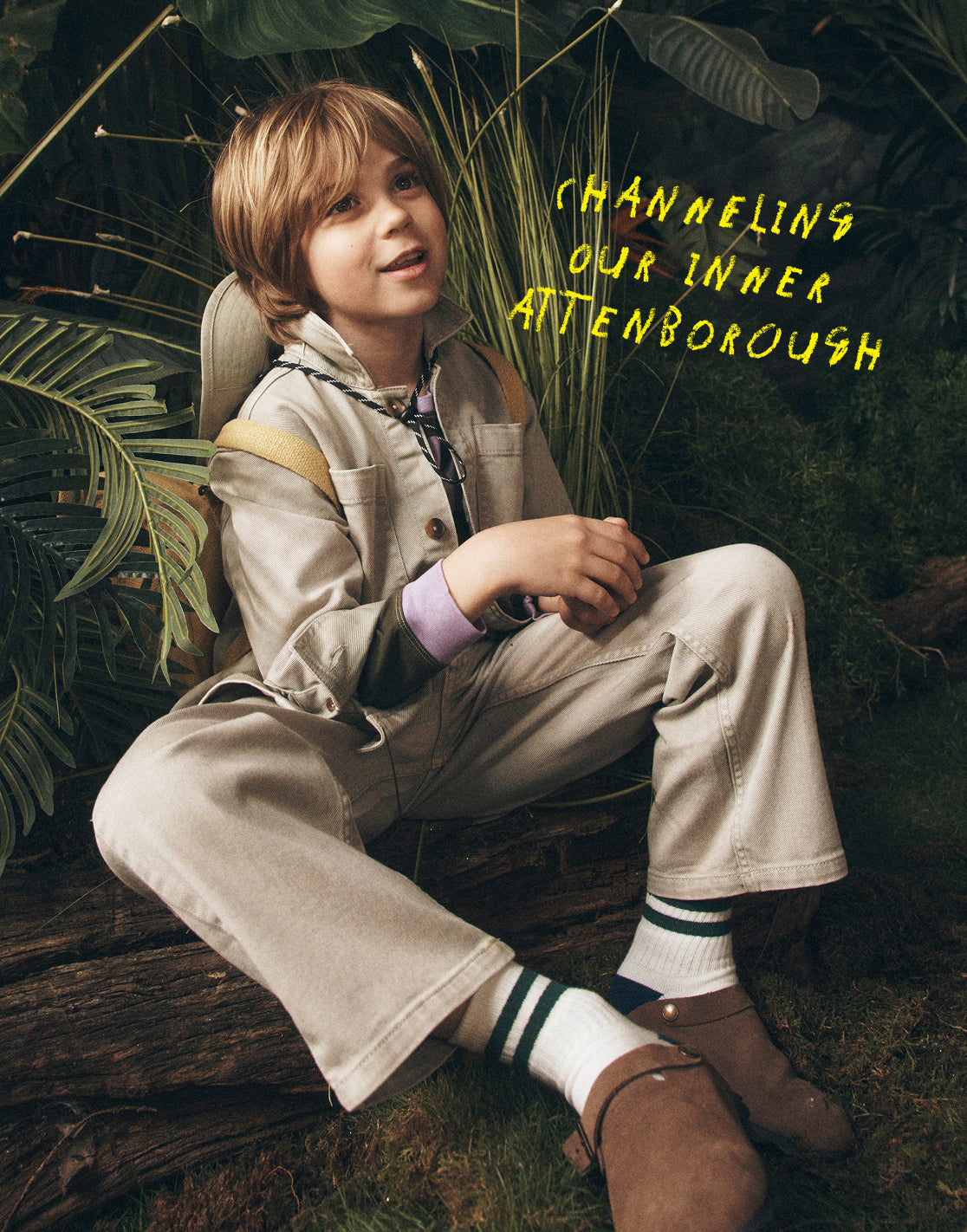 Child in a beige outfit sitting among plants with text 'CHANNELING OUR INNER ATTENBOROUGH'.