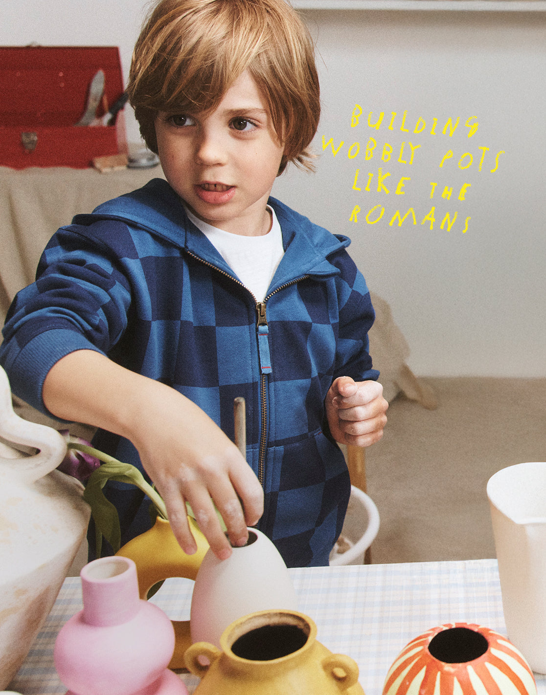 Child playing with colorful vases on a table, with text 'Building wobbly pots like the Romans' on a light background.