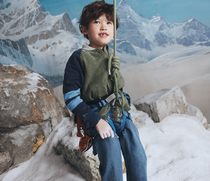 Child in climbing gear on a snowy mountain background