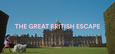 A scenic outdoor shot of a grand historic mansion on a green lawn under a clear blue sky, with large hedges framing the sides and the text 'THE GREAT BRITISH ESCAPE' across the center.