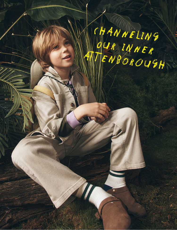 Child sitting among plants with text 'Channeling our inner Attenborough' in yellow.