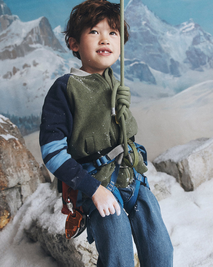 Child in climbing gear with a mountainous background