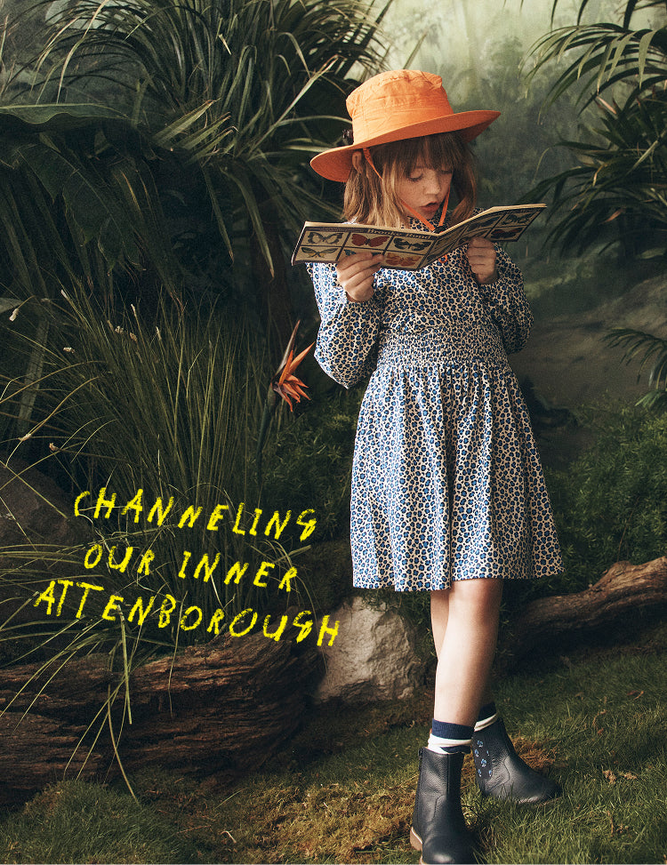 Child in a dress and hat reading a book in a forest with text 'Channeling Our Inner Attenborough'.