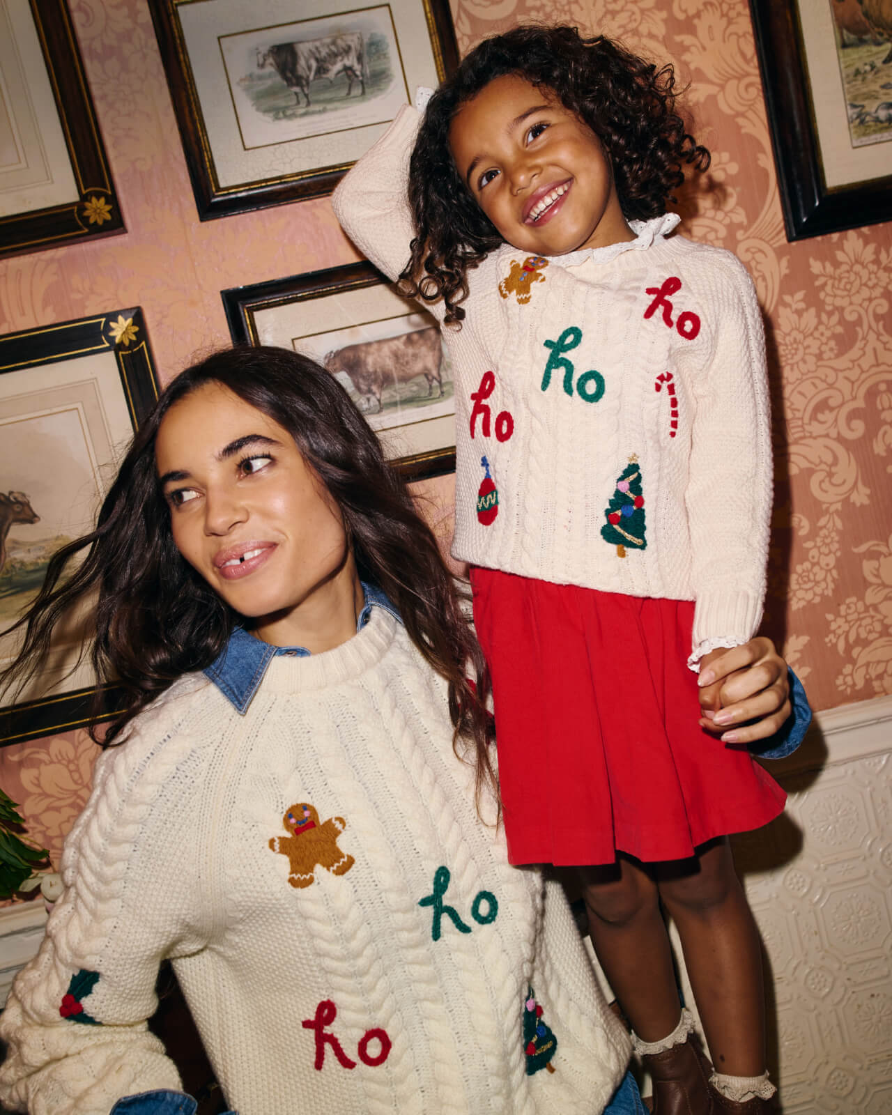 Woman with a girl wearing matching white Christmas sweaters. 